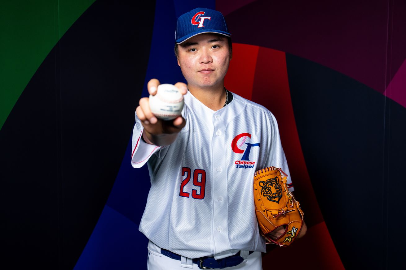Kai-Wei Teng in his WBC jersey on photo day, holding a baseball in front of him