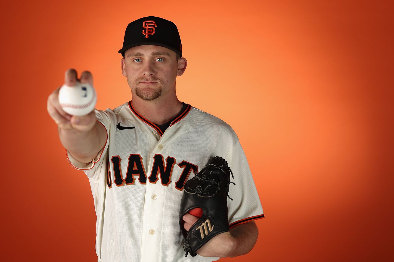 Keaton Winn holding a baseball in front of him, posing on media day
