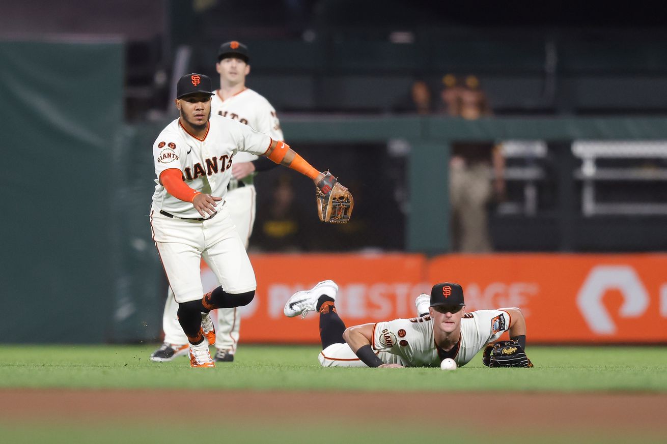 Tyler Fitzgerald lying on his belly while Thairo Estrada chases a ball.