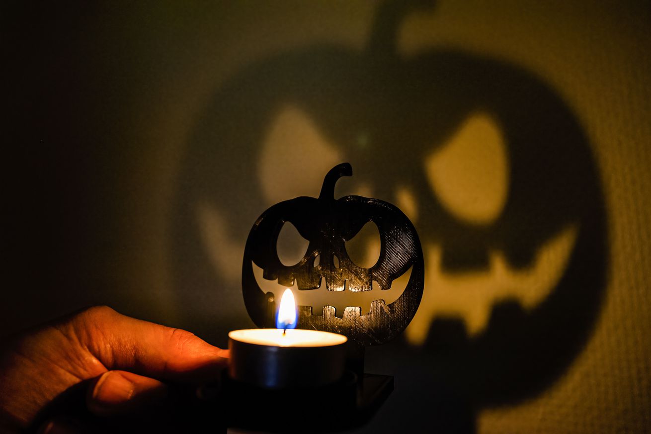 A candlelight casts a pumpkin-shaped shadow as a part of a...