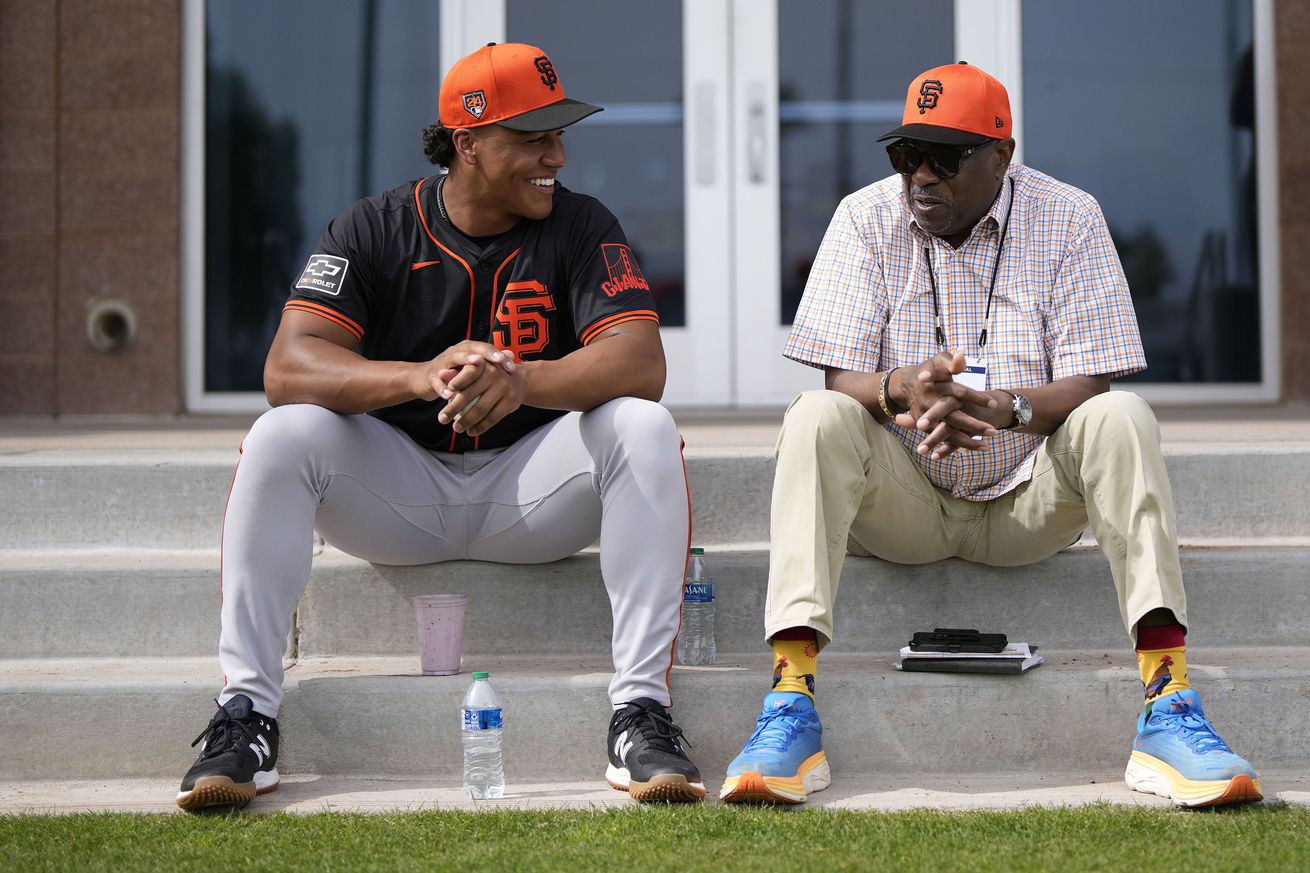 Reggie Crawford and Dusty Baker sitting on some steps at Spring Training, talking. 