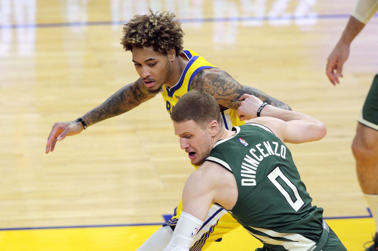 Kelly Oubre Jr. (12) and Donte DiVincenzo (0) battle for a loose ball in the first half as the Golden State Warriors played the Milwaukee Bucks at Chase Center in San Francisco Calif., on Tuesday, April 6, 2021