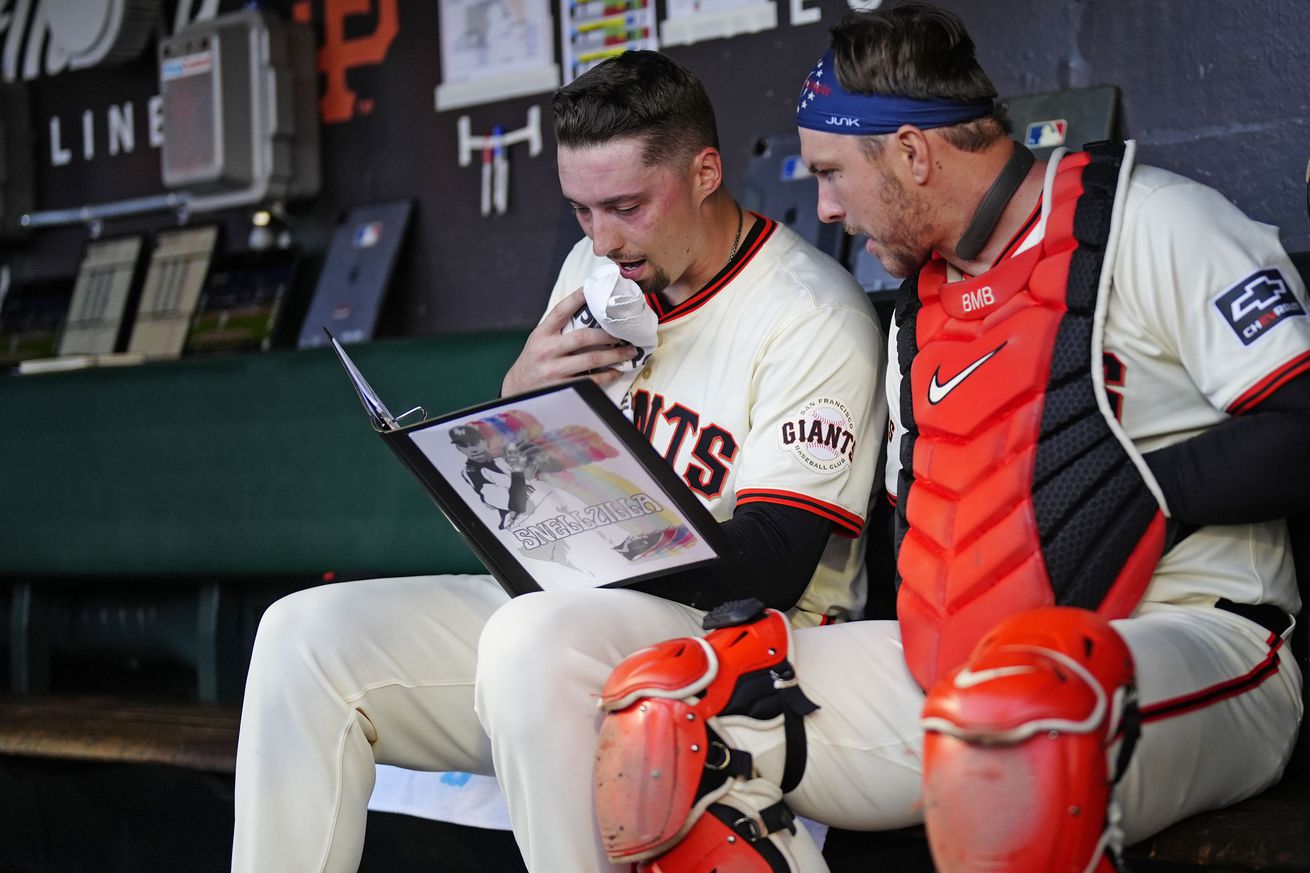 Patrick Bailey and Blake Snell sitting in the dugout reading a scouting report.