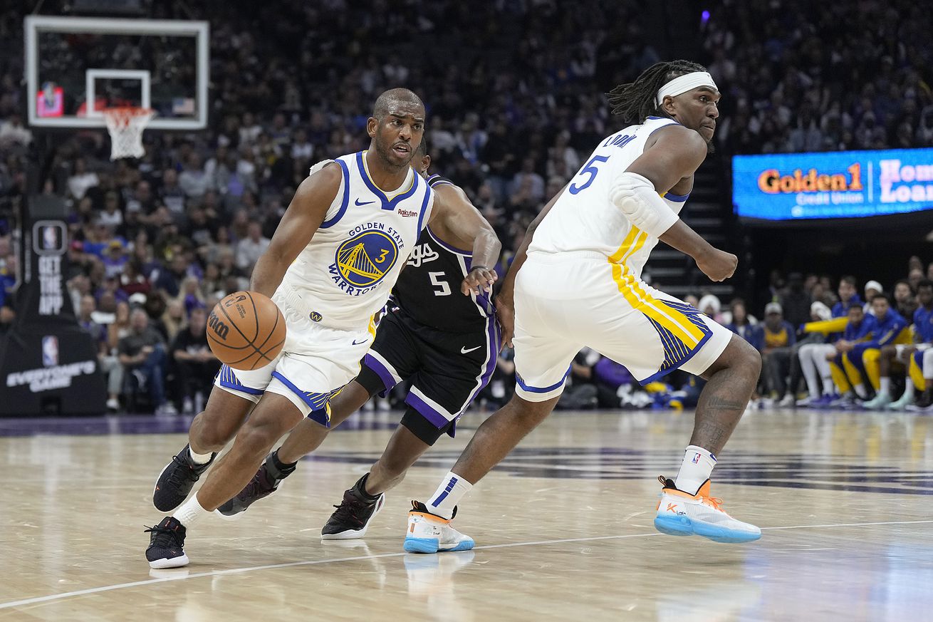 Chris Paul dribbling by De’Aaron Fox while Kevon Looney rolls to the hoop behind him. 