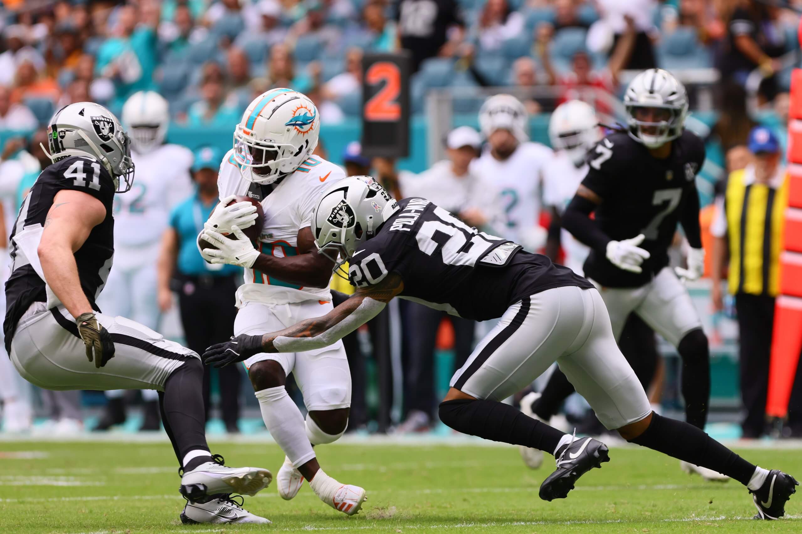 Nov 17, 2024; Miami Gardens, Florida, USA; Miami Dolphins wide receiver Tyreek Hill (10) runs with the football against Las Vegas Raiders safety Isaiah Pola-Mao (20) and linebacker Robert Spillane (41) during the first quarter at Hard Rock Stadium. Mandatory Credit: Sam Navarro-Imagn Images
