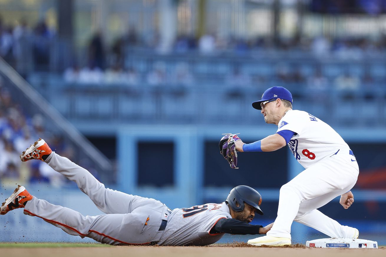 Enrique Hernández catching a ball at a bag while LaMonte Wade Jr. dives into the bag.