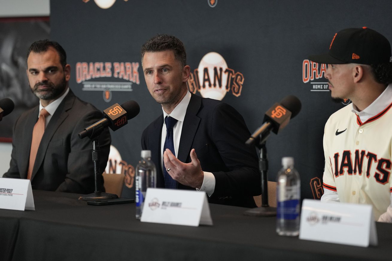 Buster Posey talking at a press conference, sitting between Zack Minasian and Willy Adames.