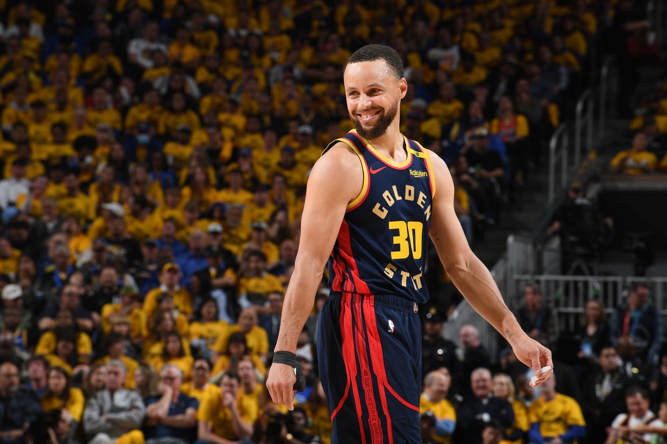 Stephen Curry #30 of the Golden State Warriors smiles during the game against the Houston Rockets during Round One Game Four of the 2025 NBA Playoffs on April 28, 2025 at Chase Center in San Francisco, California. The crowd behind him is wearing their yellow Warriors playoff shirts in support.