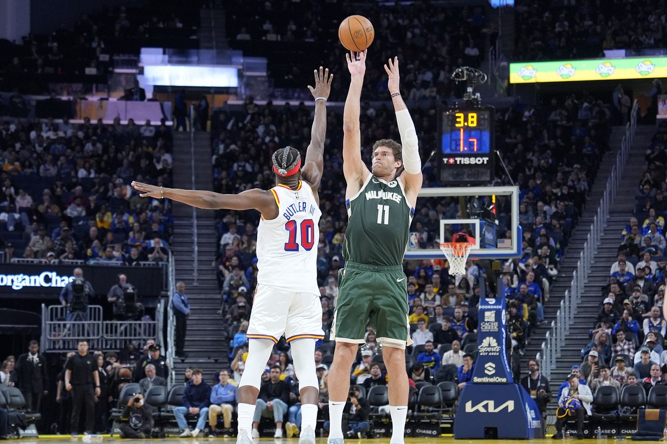 Brook Lopez shooting a three while Jimmy Butler III contests.