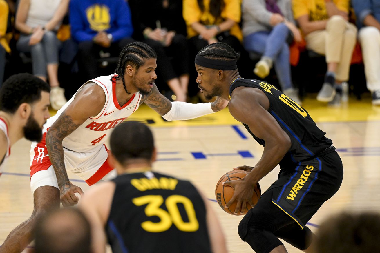 Jimmy Butler III holding the ball, defended by Jalen Green, with Steph Curry in the foreground.
