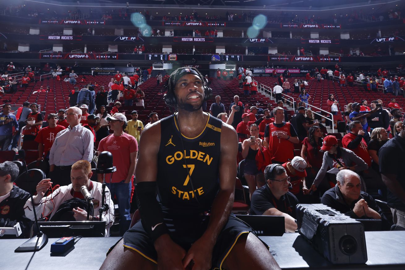 Buddy Hield sitting on the broadcast table with a headset on, talking to the media after a win.