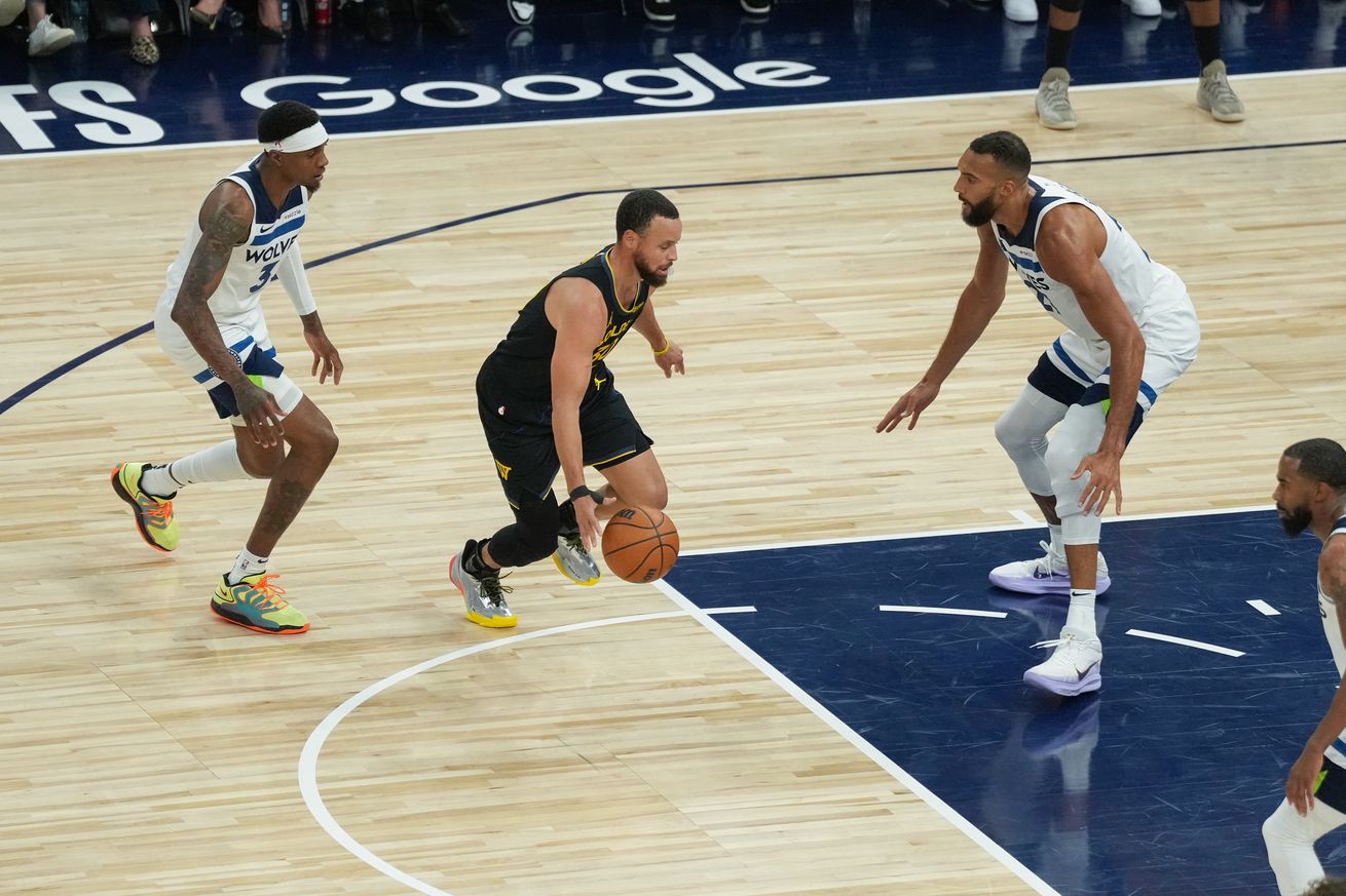 Steph Curry dribbling with his right hand between Timberwolves defenders.