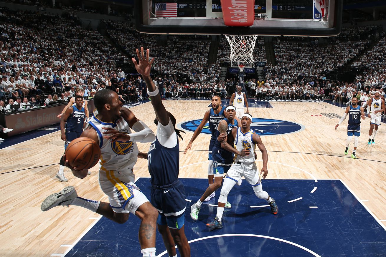 Jonathan Kuminga in the air under the rim defended by a Timberwolves player.