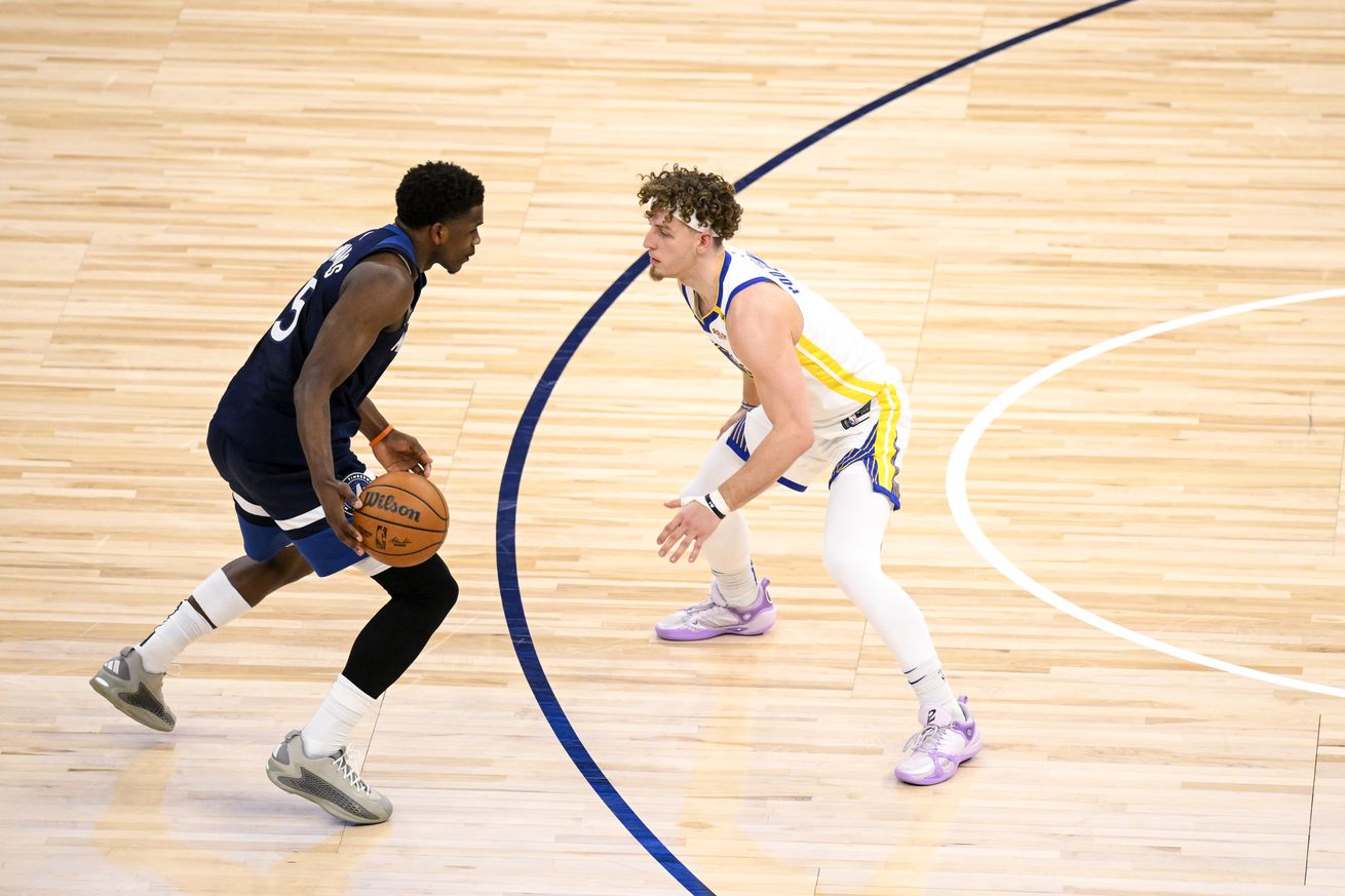 Side view of Anthony Edwards dribbling at the three-point line while defended by Brandin Podziemski.