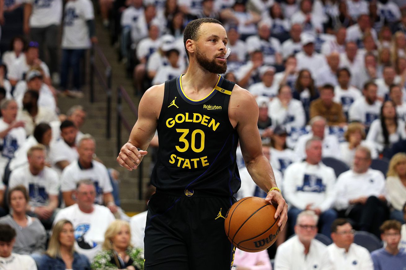 Close up of Steph Curry dribbling with the Minnesota fans behind him.