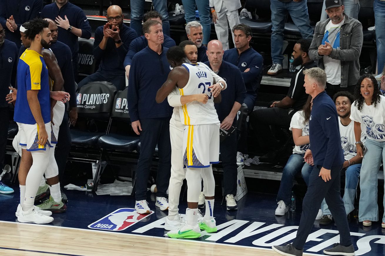Steph Curry and Draymond Green hugging on the sideline.