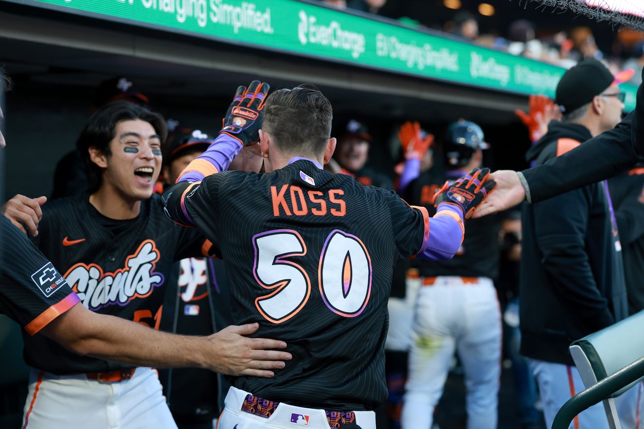 View from behind of Christian Koss entering the dugout to high-fives.