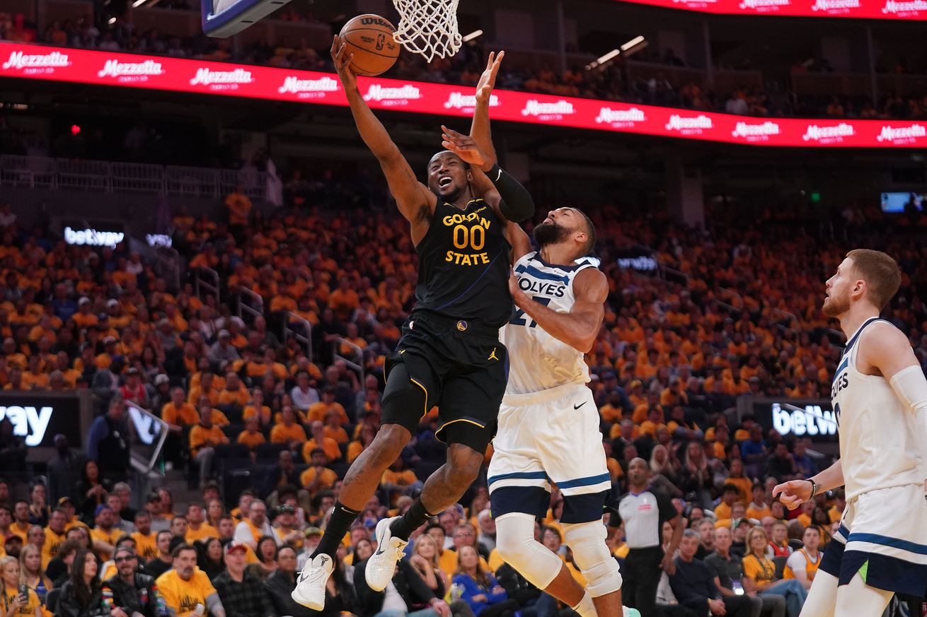 Jonathan Kuminga shooting a layup while defended by Rudy Gobert