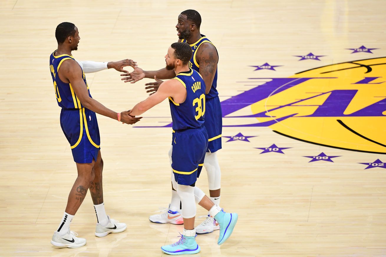 Steph Curry, Draymond Green, and Jonathan Kuminga standing on the court, making a circle with their high-fives.