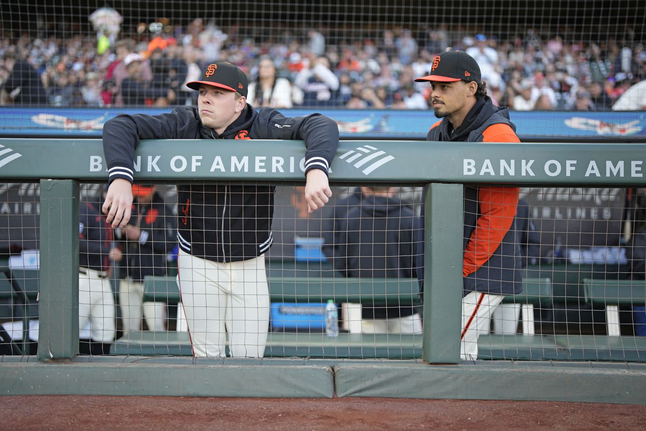 Kyle Harrison hanging over the dugout railing next to Jordan Hicks.
