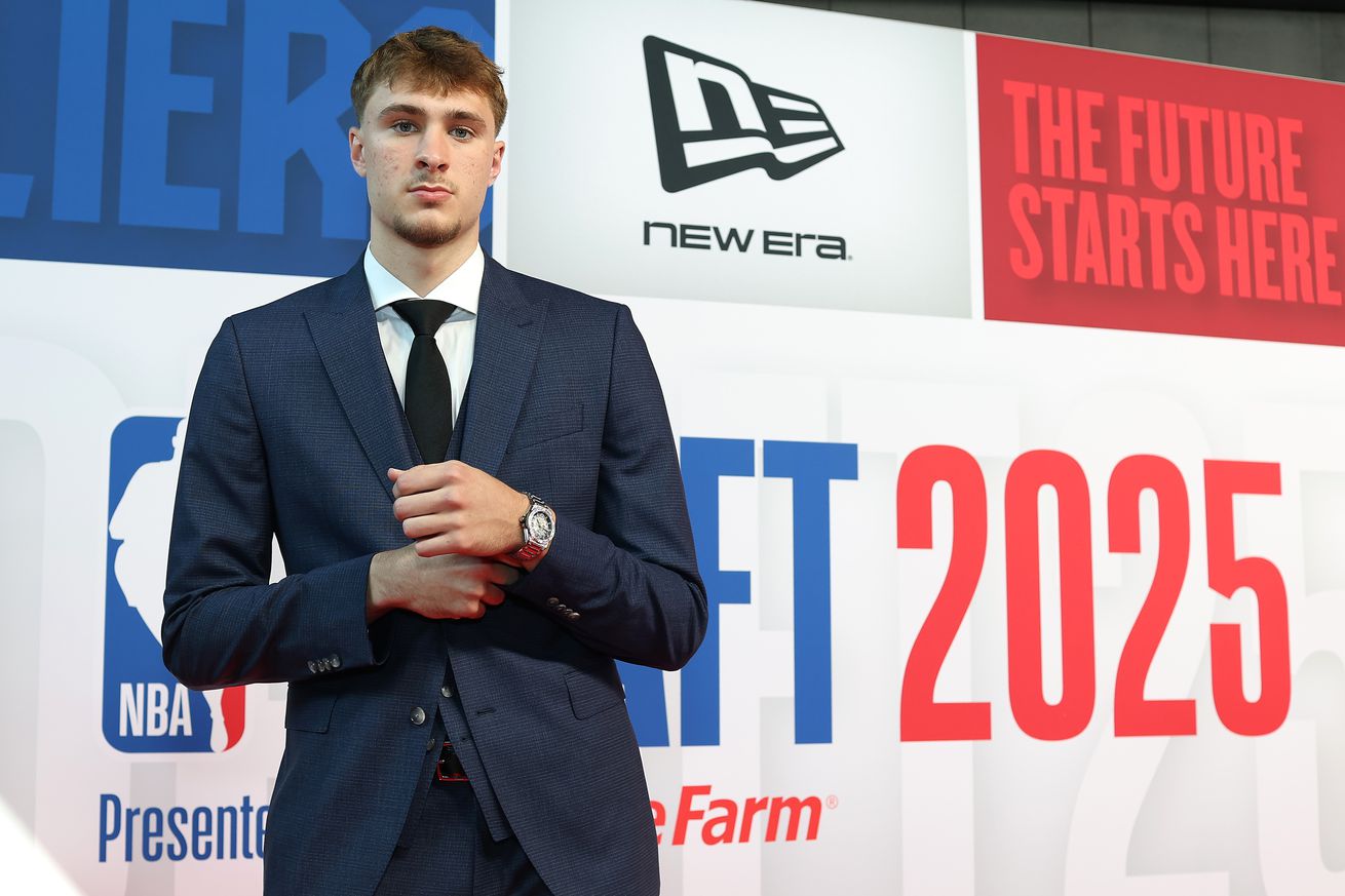 Cooper Flagg standing in front of the NBA Draft wall.
