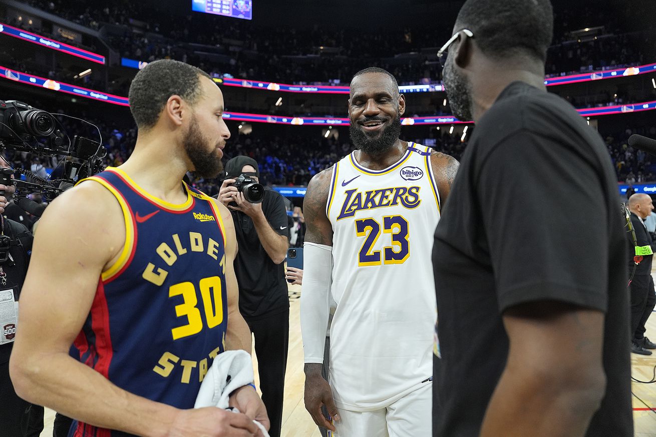 LeBron James laughing with Steph Curry and Draymond Green after a game.