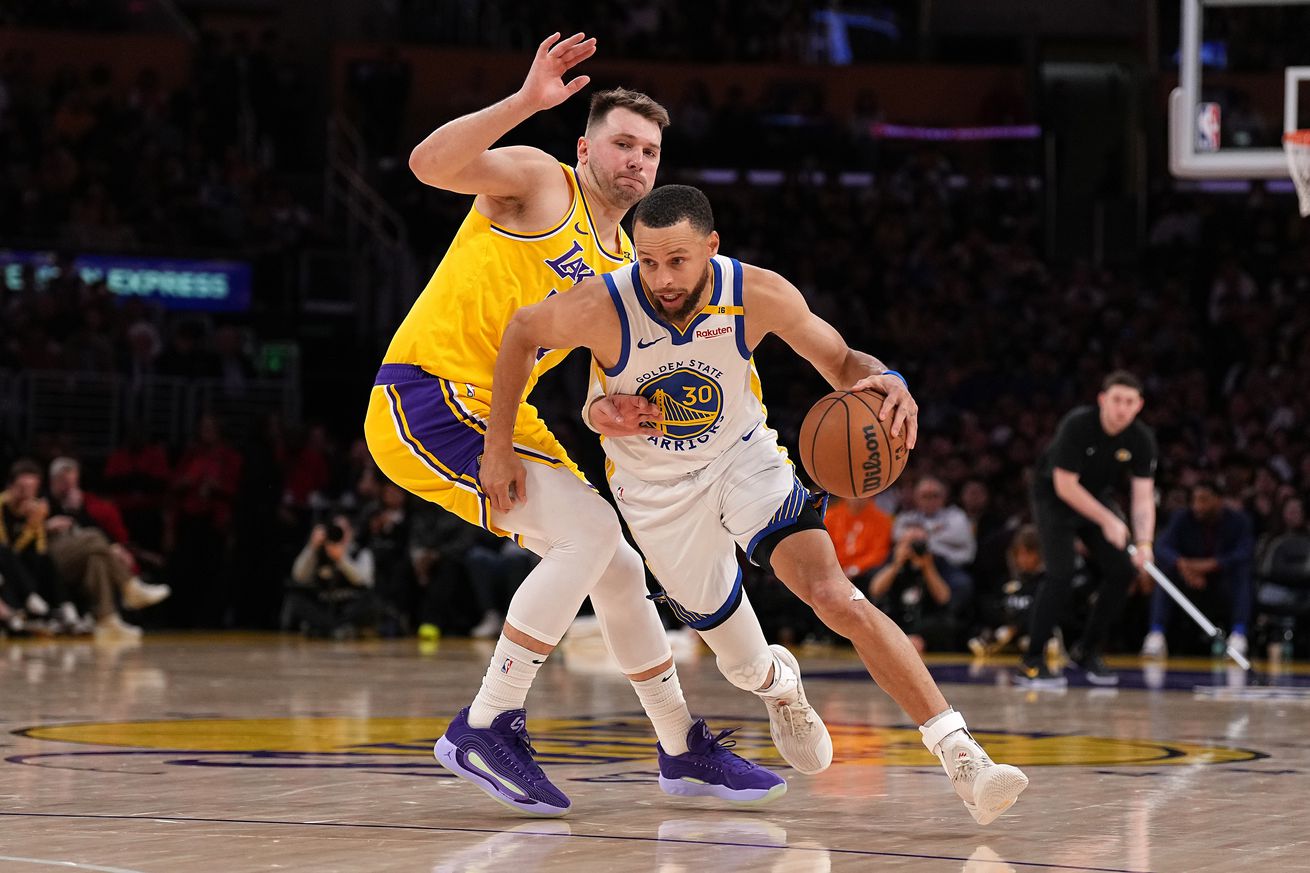Steph Curry using his left hand to dribble around Luka Dončić.