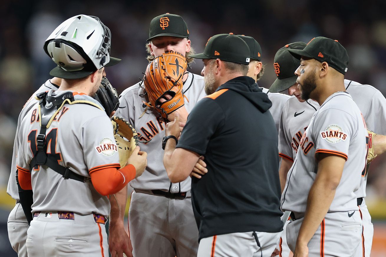 A meeting on the mound where Hayden Birdsong has his glove over his mouth. 