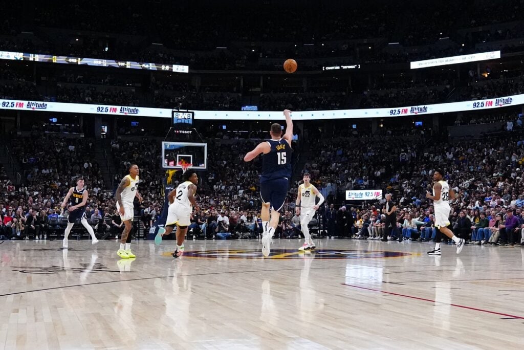 Mar 28, 2025; Denver, Colorado, USA; Denver Nuggets center Nikola Jokic (15) shoots a successful three point basket at the end of the second quarter against the Utah Jazz at Ball Arena. Mandatory Credit: Ron Chenoy-Imagn Images