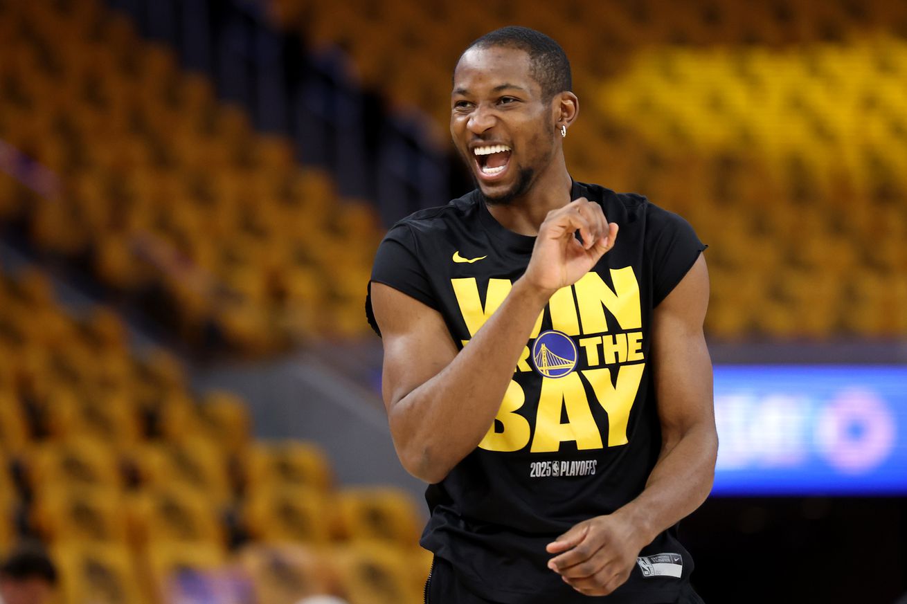 Jonathan Kuminga is smiling and wearing a black “WIN FOR THE BAY” t-shirt.